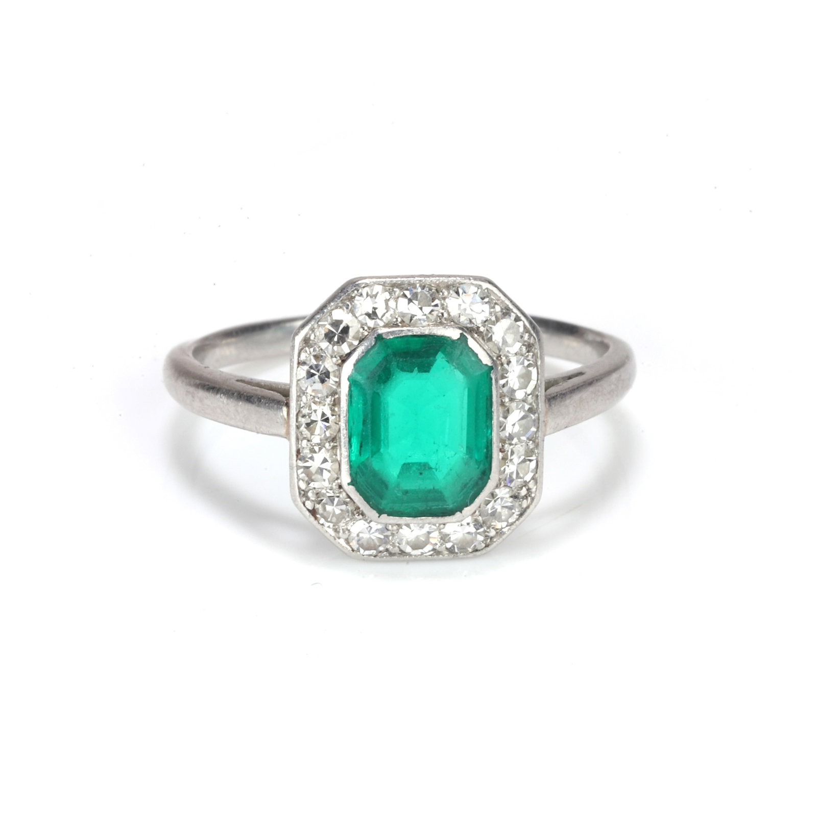 An emerald and diamond cluster ring,: An emerald and diamond cluster ring, composed of an octagonal cut emerald, rub over set, with a thread and grain set border of sixteen eight cut diamonds to a straight band, unmarked, testing as plati