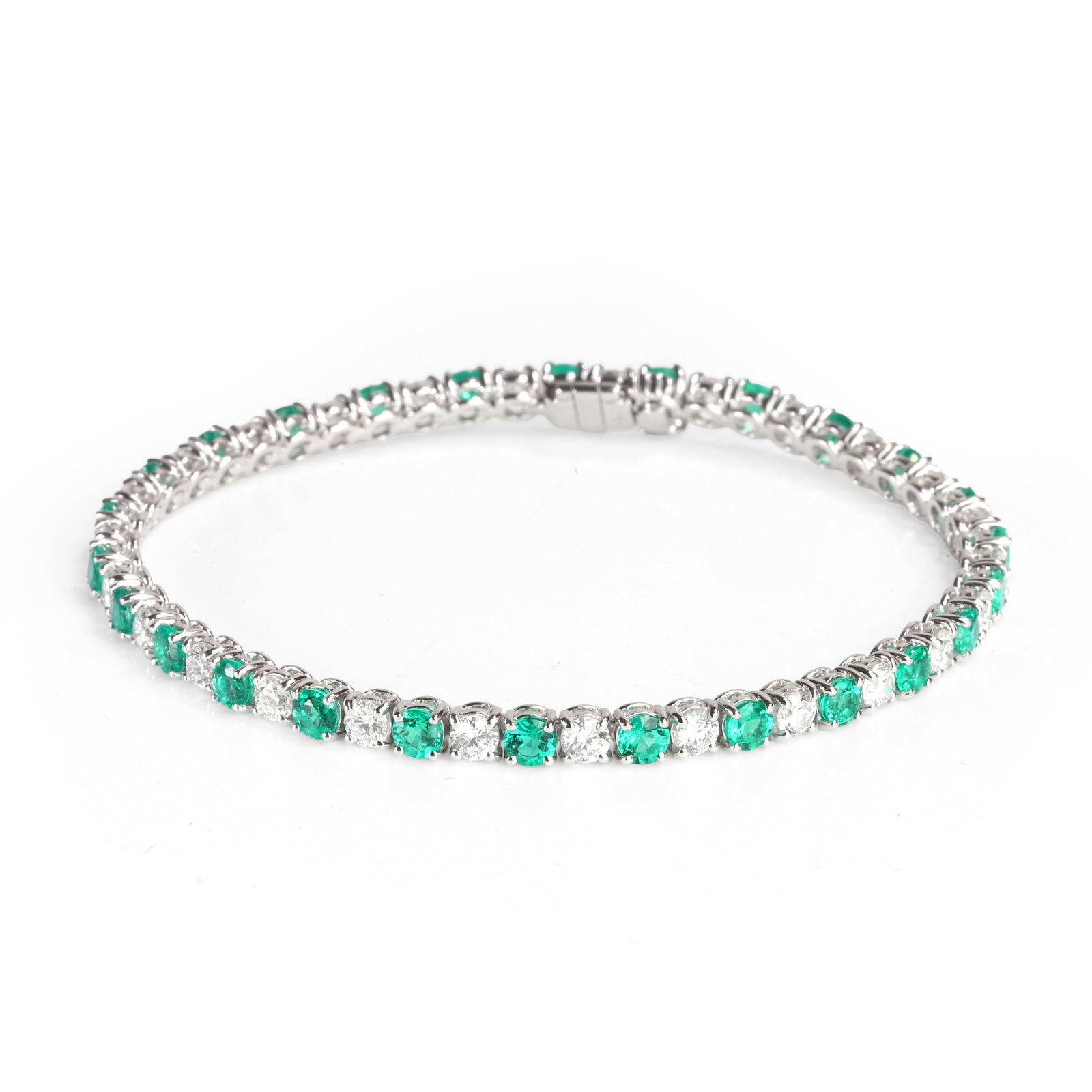 An 18ct white gold emerald and diamond line bracelet,: An 18ct white gold emerald and diamond line bracelet, designed as a line of round brilliant cut diamonds and round cut emeralds, alternately claw set in articulated collets, to a box clasp. Hallmarked