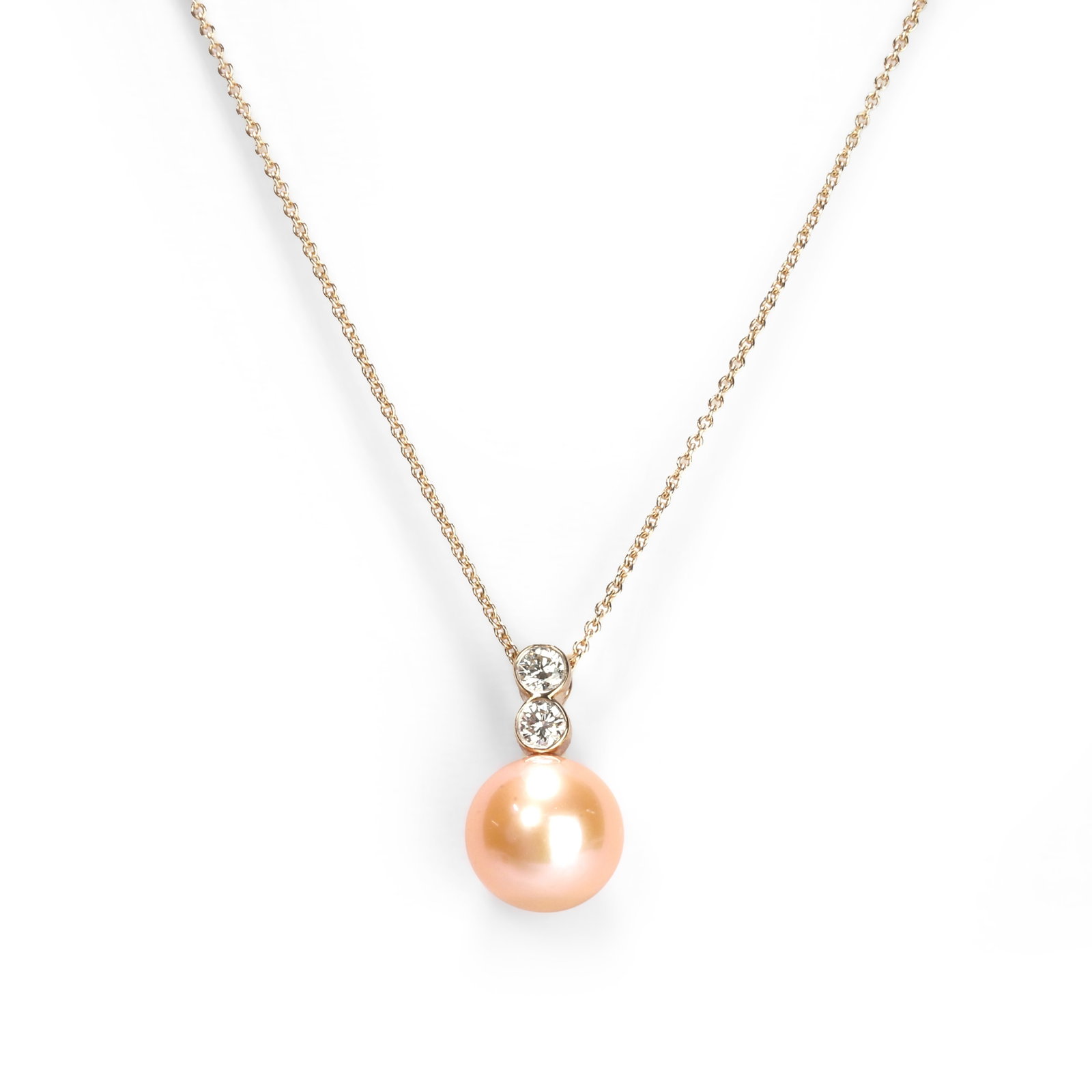 A cultured pearl and diamond pendant necklace,: A cultured pearl and diamond pendant necklace, the pink cultured pearl suspended by two round brilliant cut diamonds, on a trace link chain stamped 375 (Pendant 1.7cm; chain 45cm) Condition report: Ap