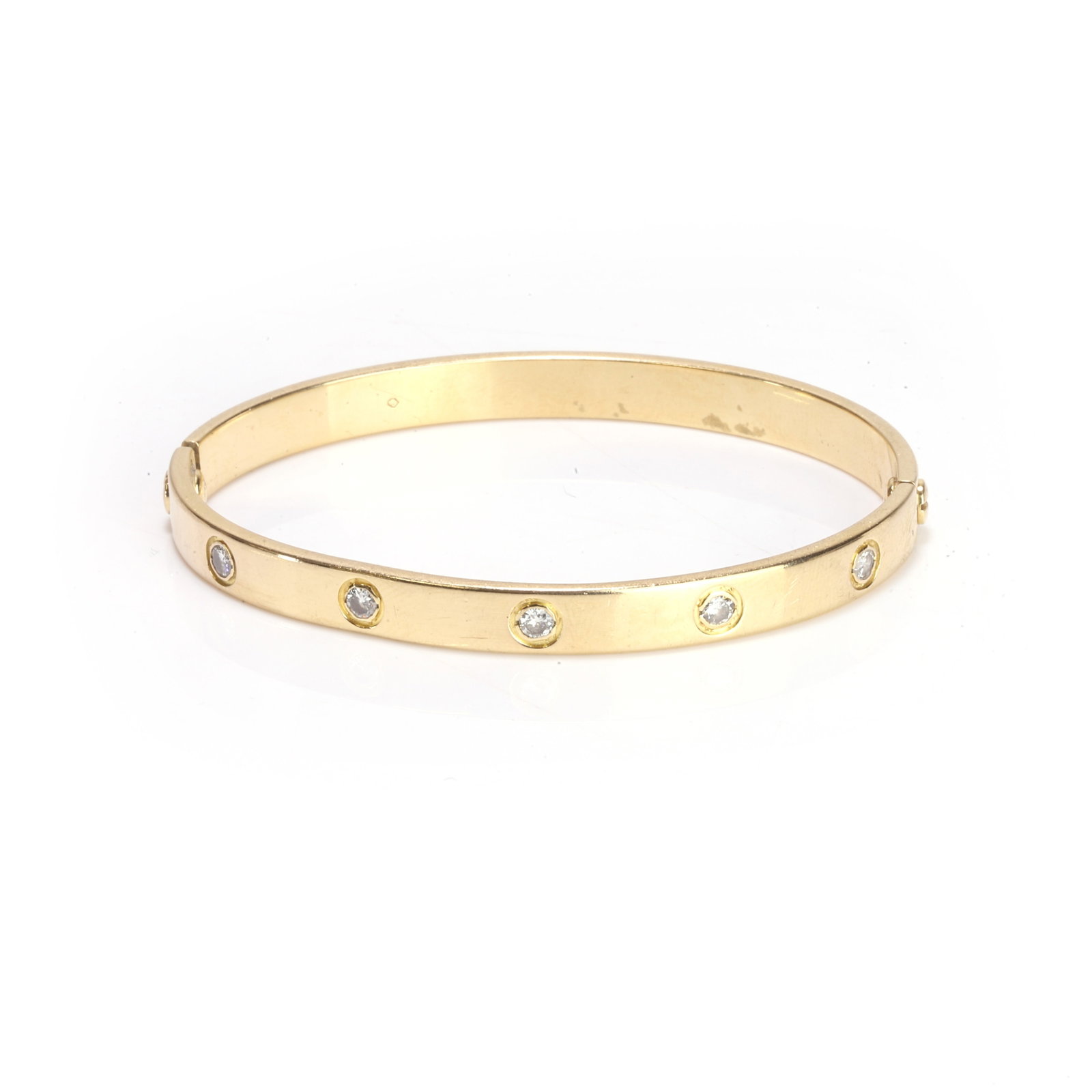 A diamond bangle,: A diamond bangle, composed of two detachable halves, one set with five round brilliant cut diamonds, the other engraved with screw motifs, in unmarked yellow metal testing as approximately 18ct gold. 