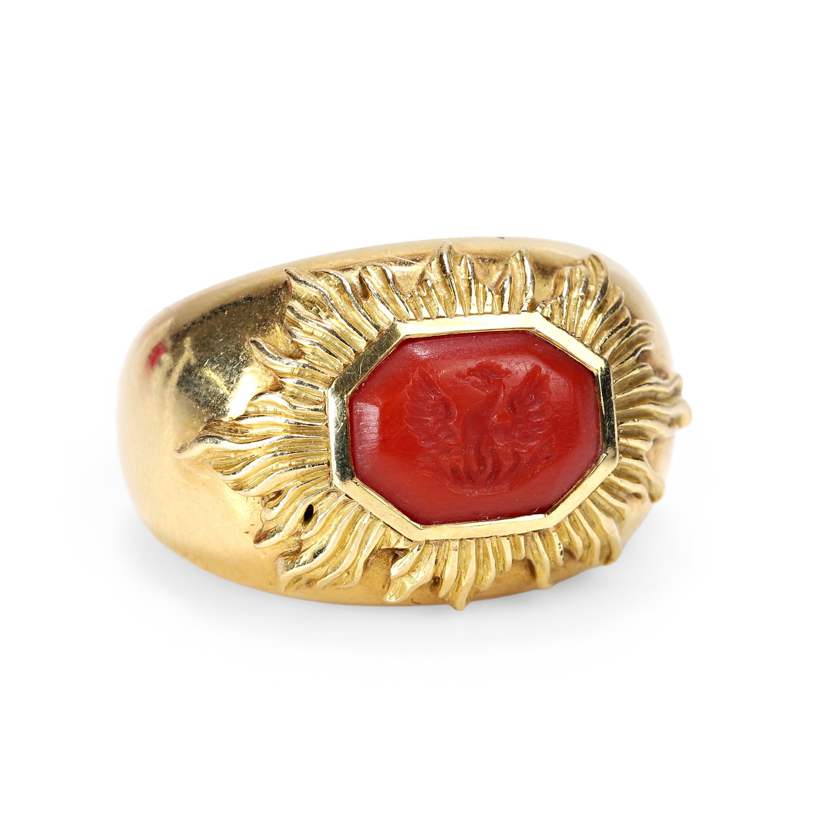 Elizabeth Gage, an 18ct gold coral intaglio signet ring,: Elizabeth Gage, an 18ct gold coral intaglio signet ring, the carved red coral tablet depicting a phoenix rising from the ashes, rub set within a raised sunburst surround, into a wide band with sizing 