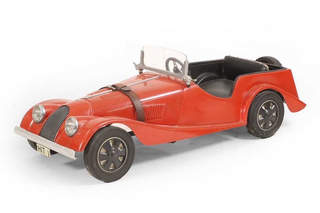 A Morgan 4/4 pedal car, circa mid-20th century,: A Morgan 4/4 pedal car, circa mid-20th century, fibreglass, finished in red, with rubberised tyres over plastic wheels, and nickel-plated brass windscreen fittings (44cm wide, 122cm long) (1)