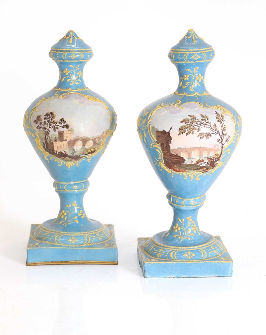 A matched pair of Birmingham enamelled landscape vases, late 18th century,: A matched pair of Birmingham enamelled landscape vases, late 18th century, of urn shape, in the Sèvres style, with a bleu cèleste ground, both with cartouches of fishermen in riverside