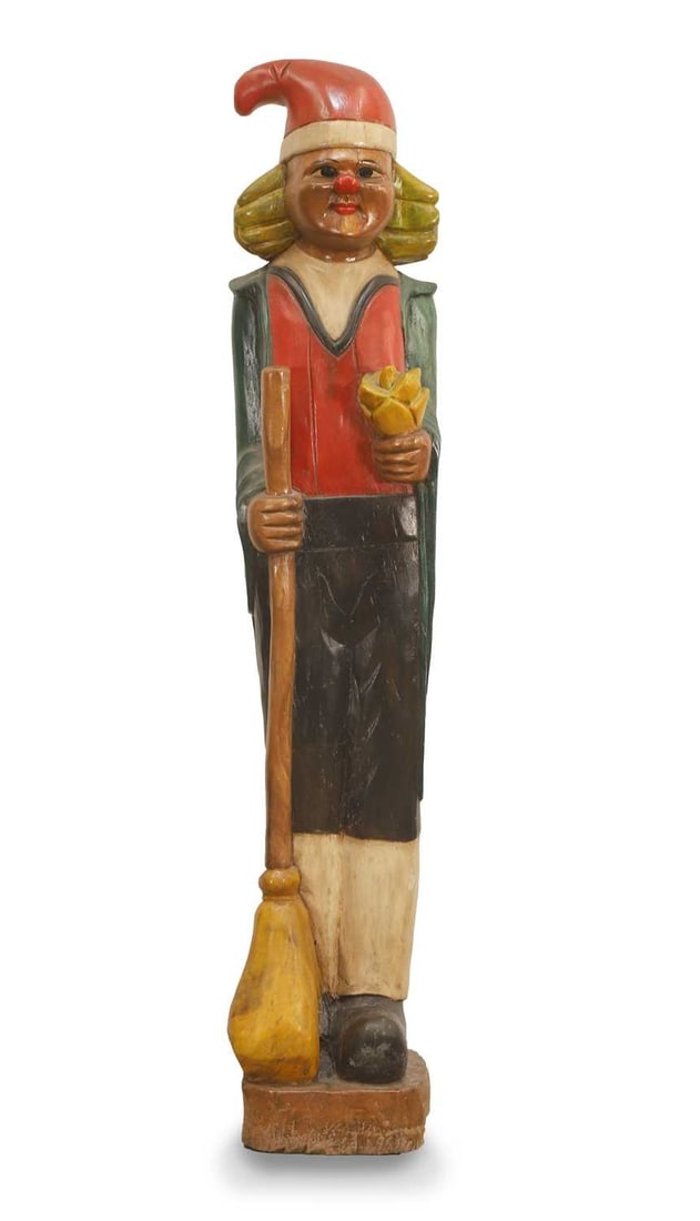 A wooden folk art elf, 20th century,: A wooden folk art elf, 20th century, possibly European, modelled holding a broom, wearing a Chistmas hat and with rosy nose