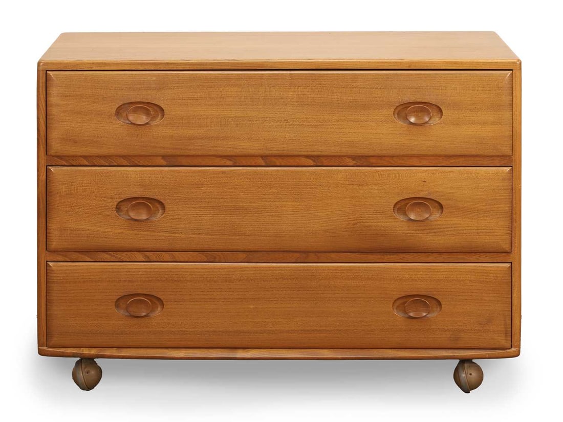 An Ercol 'Windsor' chest of drawers, circa 1960s, designed by Lucian Ercolani,: An Ercol 'Windsor' chest of drawers, circa 1960s, designed by Lucian Ercolani, Model 483 commode in blonde elm, with three long drawers, to a castored base