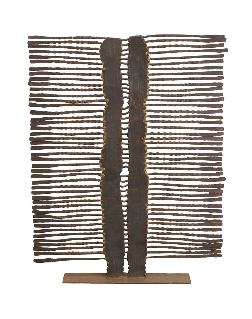 A contemporary metal fire screen of tribal influence,: A contemporary metal fire screen of tribal influence, formed as a series of textured and undulating vertical and horizontal elements, mounted on a rectangular plinth base with dark patinated finish