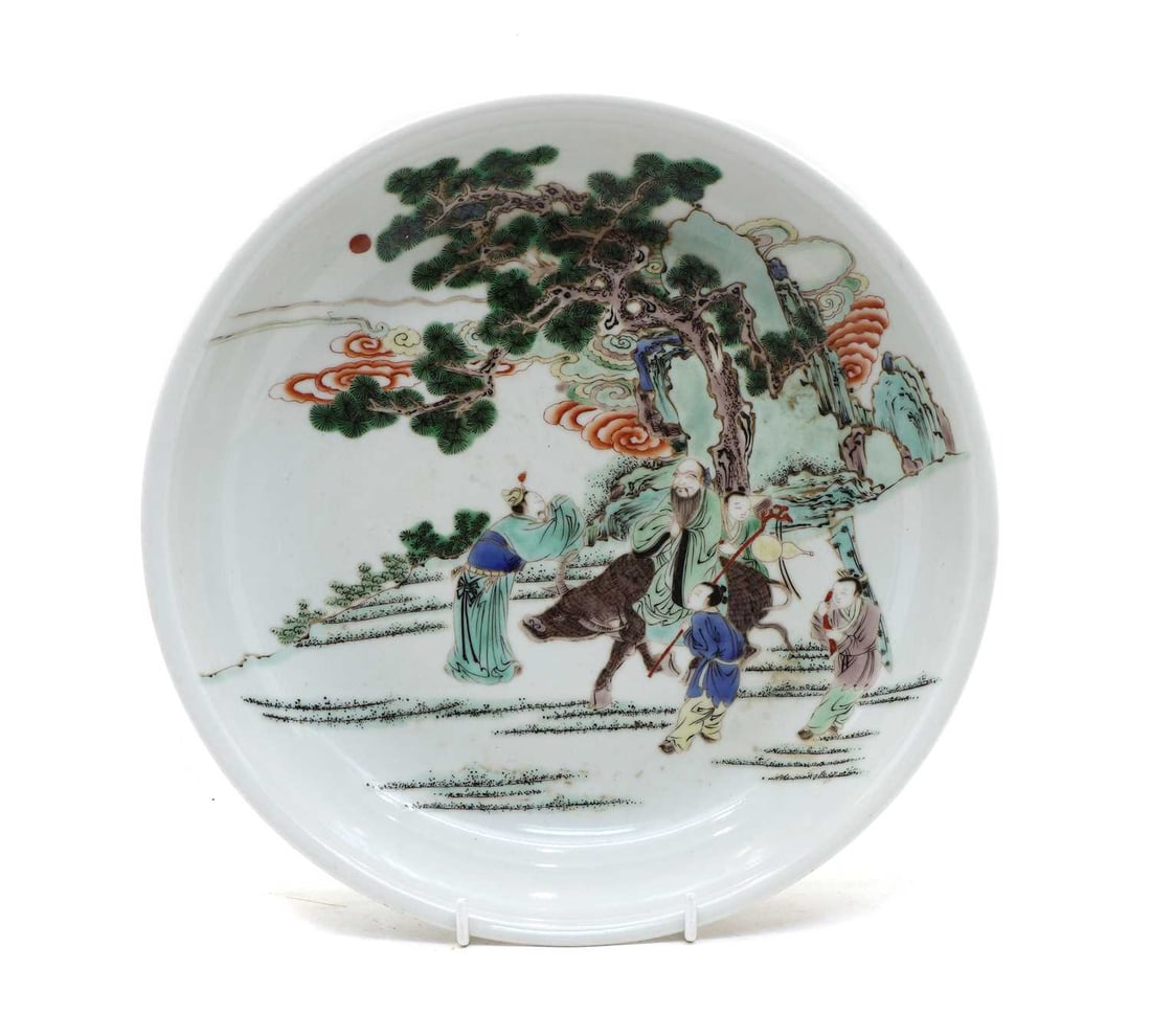 A Chinese famille verte plate,: A Chinese famille verte plate, the rounded sides rising from a channelled circular foot to a flared rim, painted with Laozi seated on a water buffalo under a pine tree in a rocky landscape, attendants