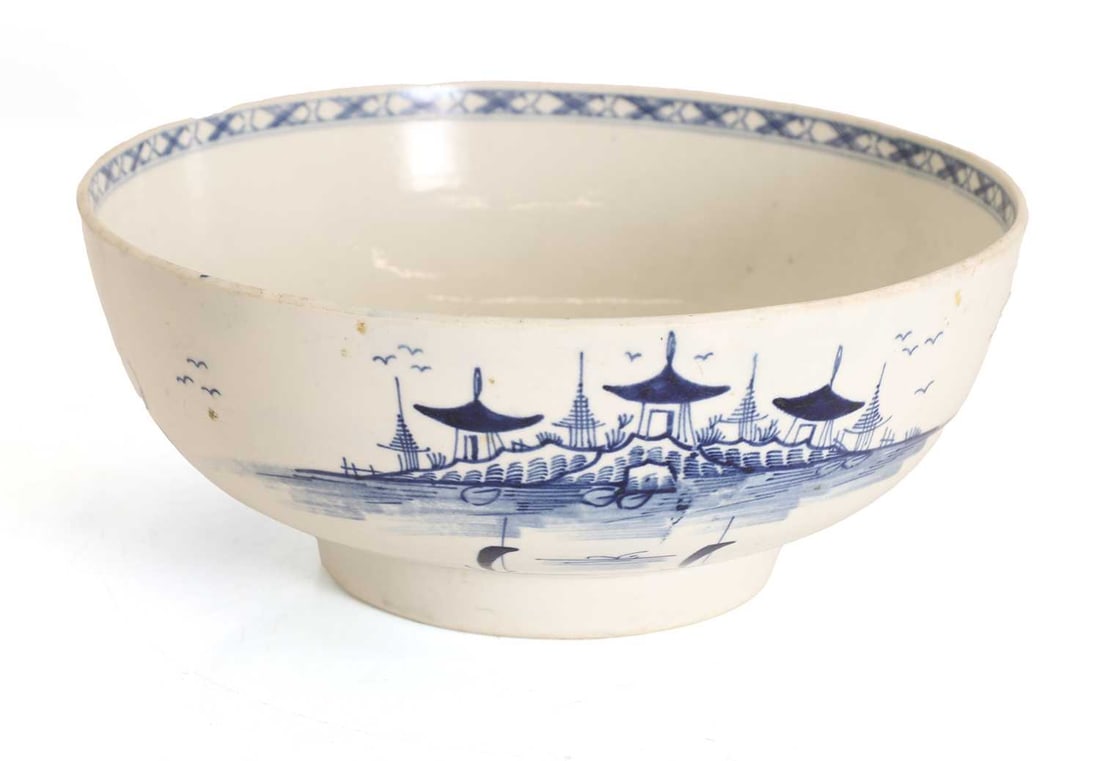 A Worcester blue and white bowl, mid 18th century,: A Worcester blue and white bowl, mid 18th century, decorated in the Chinese style, decorated with a village scene to the exterior and the centre with a tree, with blue crescent moon mark to the base