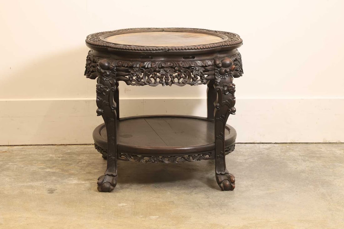 A Chinese low table, 19th / 20th century,: A Chinese low table, 19th / 20th century, the top decorated with foliage and a beaded edge, above a circular undertier and a frieze profusely carved with fruiting vines and foliage, the supports in