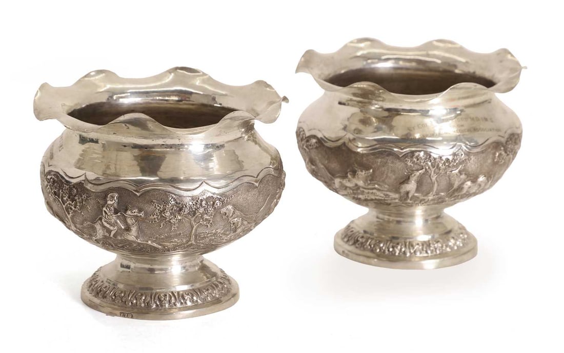 A pair of Indian silver-plated pedestal bowls, circa 1930s, India, West Bengal, Darjeeling,: A pair of Indian silver-plated pedestal bowls, circa 1930s, India, West Bengal, Darjeeling, the bulbous body cast in relief with tigers, trees, buffalo, and mounted figures, the neck engraved with