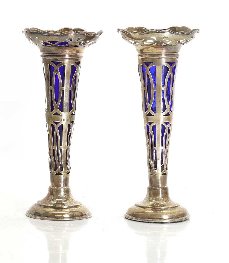 A pair of Art Deco silver bud vases,: A pair of Art Deco silver bud vases, by William Hair Haseler, Birmingham, 1907, with blue glass liners, filled 19cm high, overall without liners, 9.8ozt 2 Condition Report: One is warped and the vase