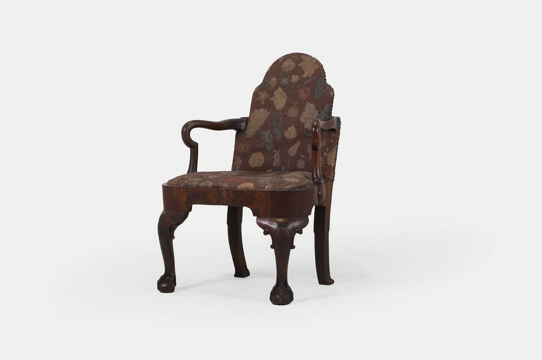 A George II walnut armchair, second quarter of the 18th century and later,: A George II walnut armchair, second quarter of the 18th century and later, the upholstered arched back and drop-in seat flanked by shepherd's crook arms, the carved cabriole front legs terminating in 