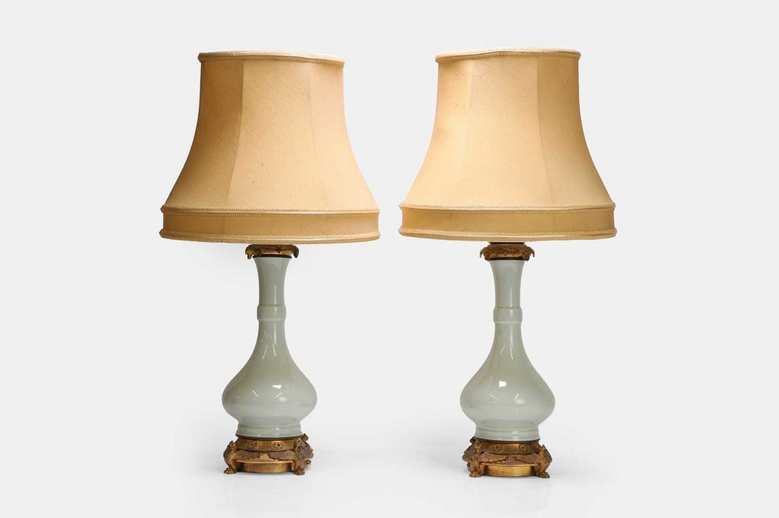 A pair of celadon vase lamps, 20th century, Chinese,: A pair of celadon vase lamps, 20th century, Chinese, each of ovoid baluster form, mounted on a gilt-metal base with dragon finials and paw feet (16cm wide, 43cm high) (2) Condition Report: One vase is