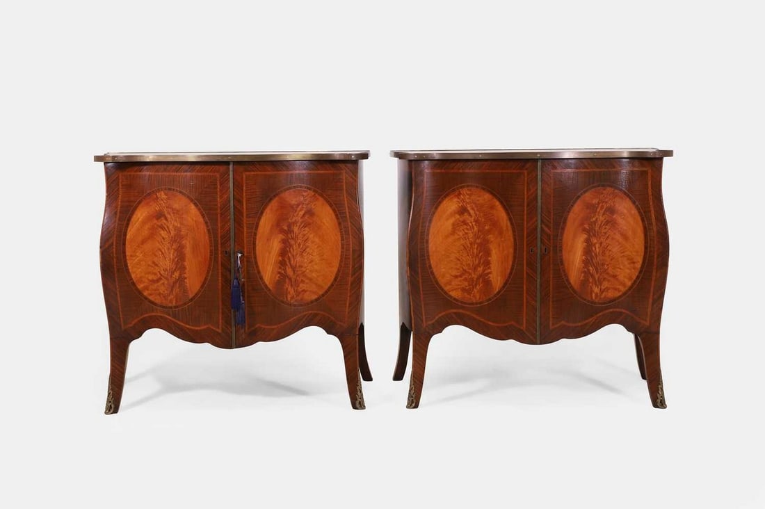 A pair of George III-style mahogany and satinwood pier cabinets, early 20th century,: A pair of George III-style mahogany and satinwood pier cabinets, early 20th century, each crossbanded serpentine surface above crossbanded cupboard doors centred with inlaid roundels, raised on splaye