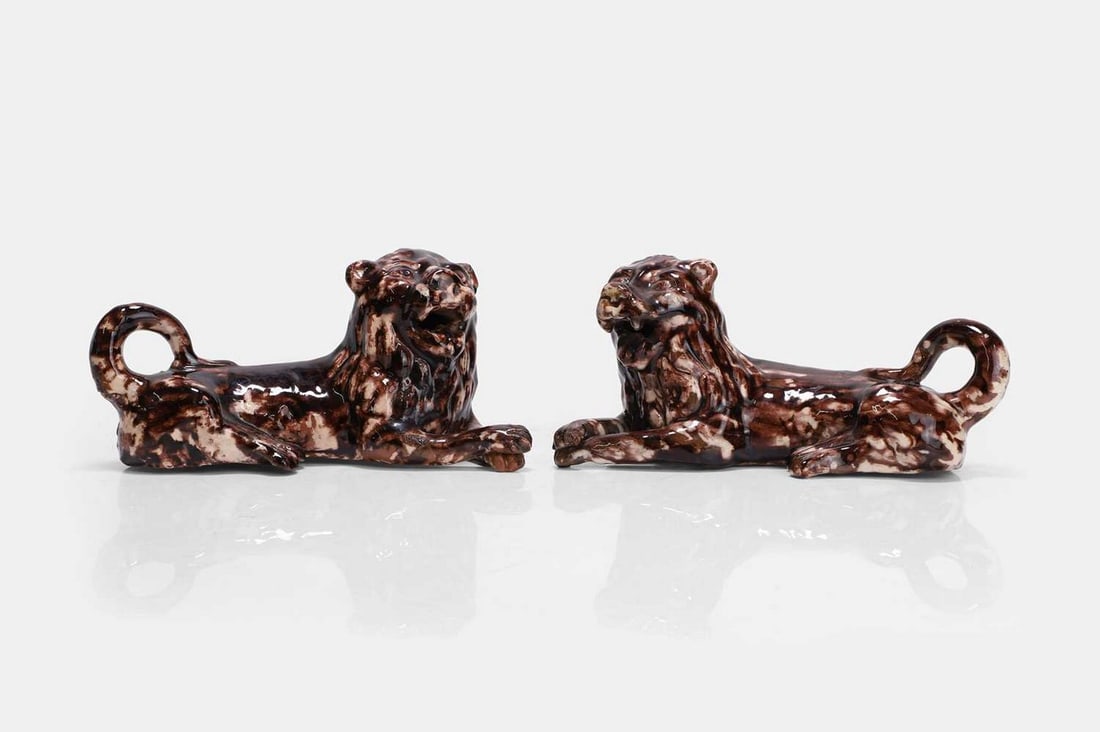 A pair of Whieldon-type pottery lions, second half of the 18th century,: A pair of Whieldon-type pottery lions, second half of the 18th century, each modelled in a recumbent pose (22cm long, 10cm wide, 10cm high) (2)