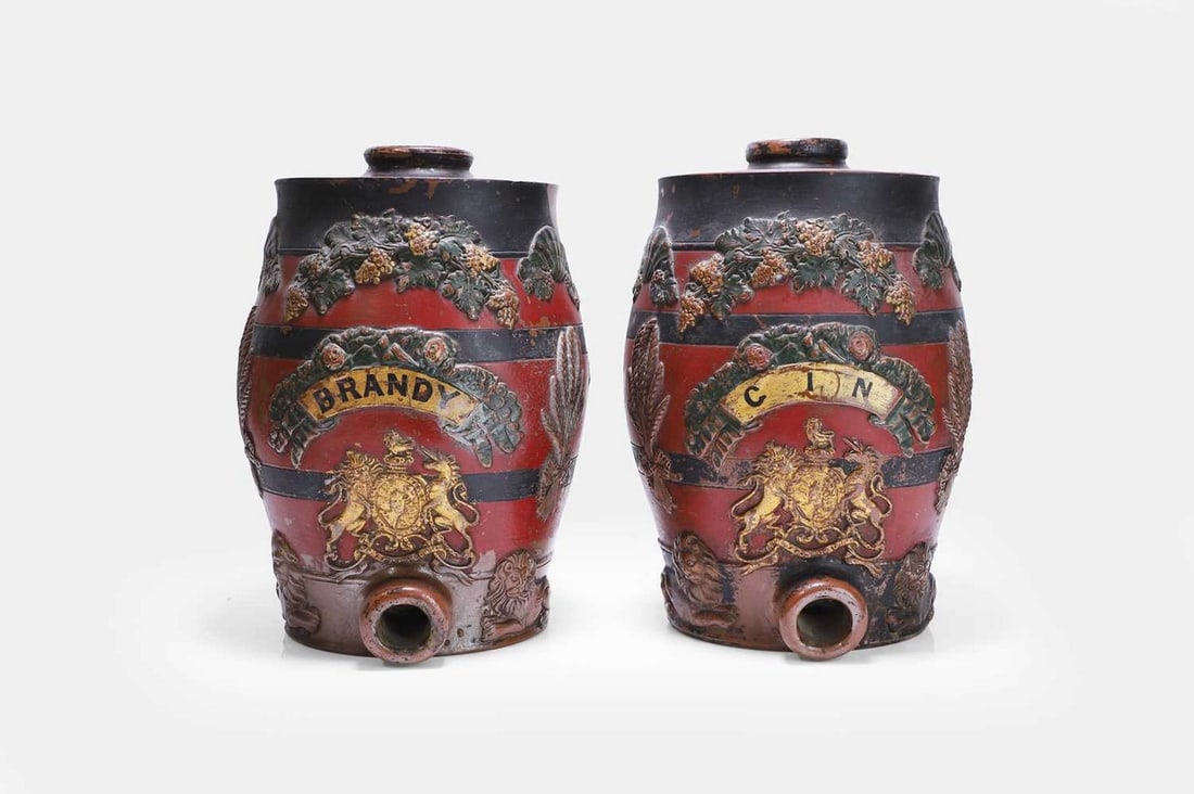A pair of stoneware spirit barrels, 19th century,: A pair of stoneware spirit barrels, 19th century, labelled 'Gin' and 'Brandy', later polychrome decorated and gilded with Royal Arms (21cm diameter, 33cm high) (2) Provenance: The Collection of James 