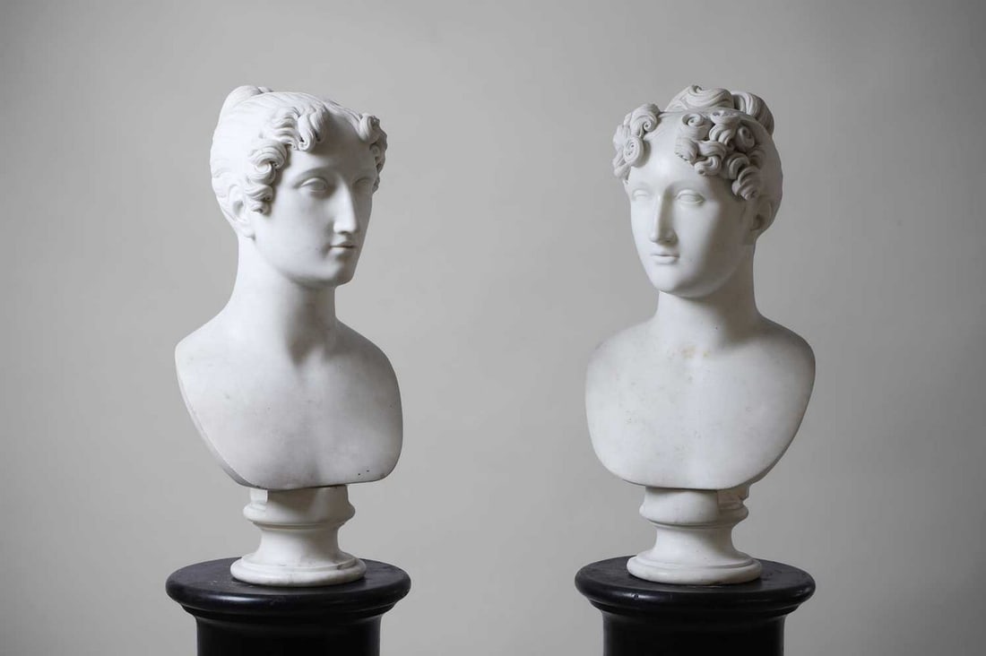 Two Regency white marble portrait busts, circa 1820-30s,: Two Regency white marble portrait busts, circa 1820-30s, each depicting a woman, the hair of highly stylised curls pulled into a bun and a French knot respectively, with a wide centre parting and ring