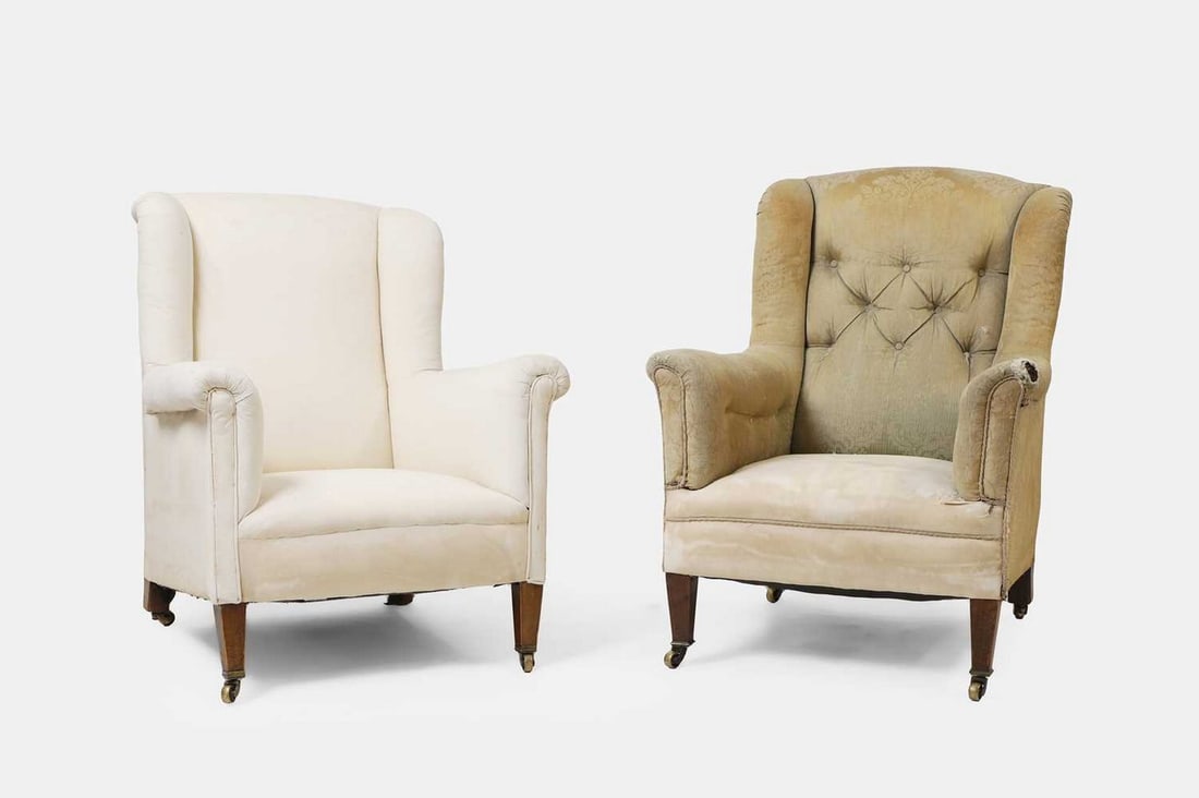 A near pair of armchairs, early 20th century, in the manner of Howard and Sons,: A near pair of armchairs, early 20th century, in the manner of Howard and Sons, each with a wing back and rollover arms, raised on square tapering legs terminating in brass castors (tallest chair 70cm