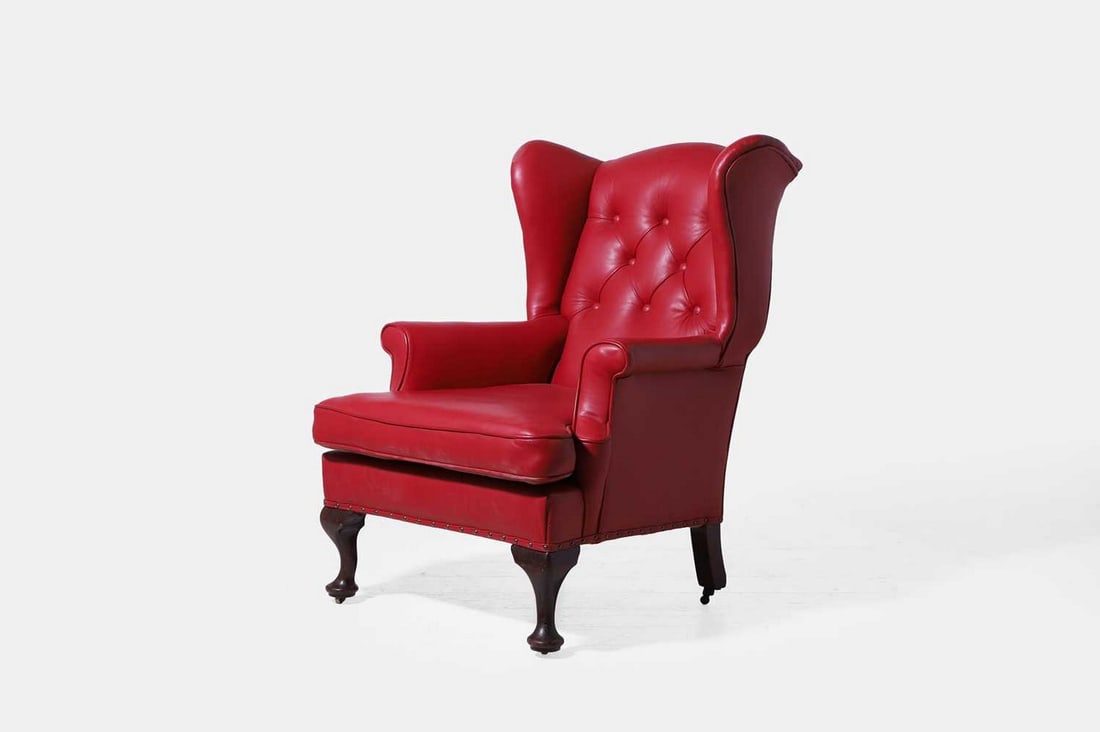 A Queen Anne-style mahogany wing armchair, late 19th century,: A Queen Anne-style mahogany wing armchair, late 19th century, the buttoned red leather upholstery supplied by David Hicks, raised on cabriole front supports terminating in brass caps and castors (77cm