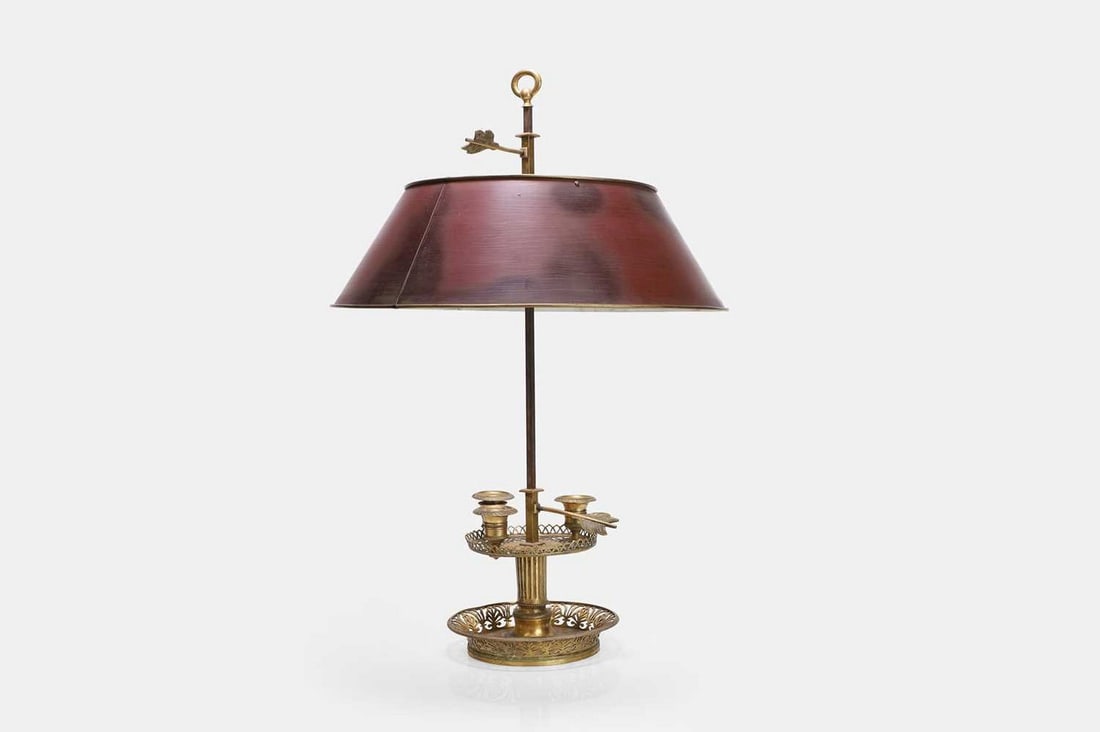 A Restoration ormolu bouillotte lamp, first quarter of the 19th century,: A Restoration ormolu bouillotte lamp, first quarter of the 19th century, the adjustable red tole shade above three brass sconces in the form of urns, raised on a pierced brass dished base, with arrow 