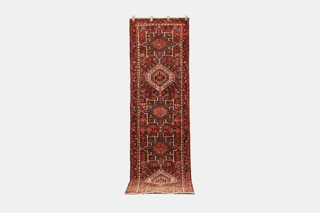 A Heriz wool runner, of recent manufacture,: A Heriz wool runner, of recent manufacture, woven with geometric motifs and medallions to a red ground (306 x 83cm) Condition Report: The actual colour of the lot may vary from images in the auction c