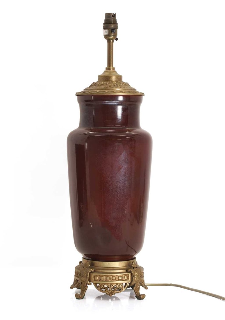 A large sang de boeuf table lamp, 20th century,: A large sang de boeuf table lamp, 20th century, with gilt metal mounts and terminating on scrolled feet, with a cream shade 60cm high Provenance: The contents of Thornton House, Clare. Condition