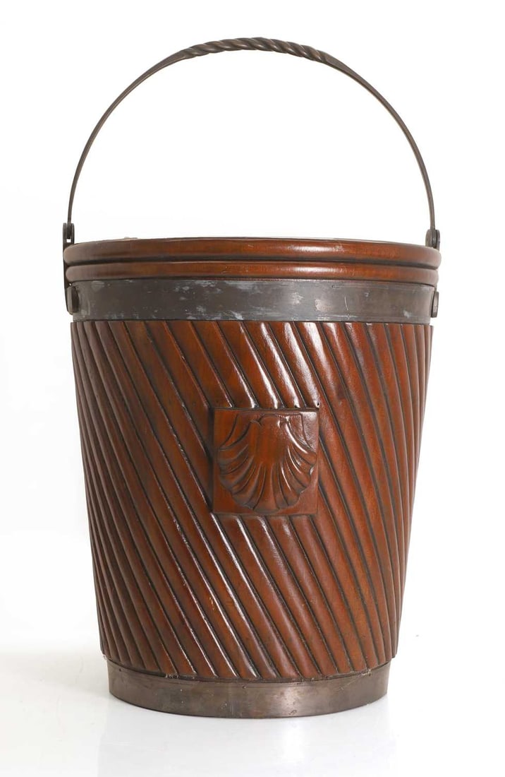 A mahogany peat bucket, 20th century,: A mahogany peat bucket, 20th century, fitted with a brass liner and swing handle, carved on both sides with a shell motif 41cm diameter, 68cm high Condition Report: Brass tarnished, with light knocks