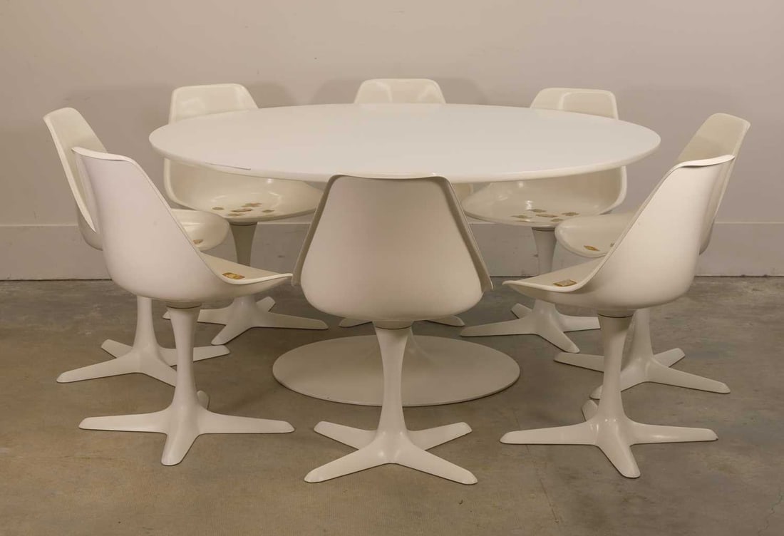 An Arkana table and eight chairs, circa 1970s,: An Arkana table and eight chairs, circa 1970s, with a circular white top, raised on a tulip stand, the chairs with revolving sprung seats, without cushions, 151.5cm diameter, 74cm high, chairs, 51cm
