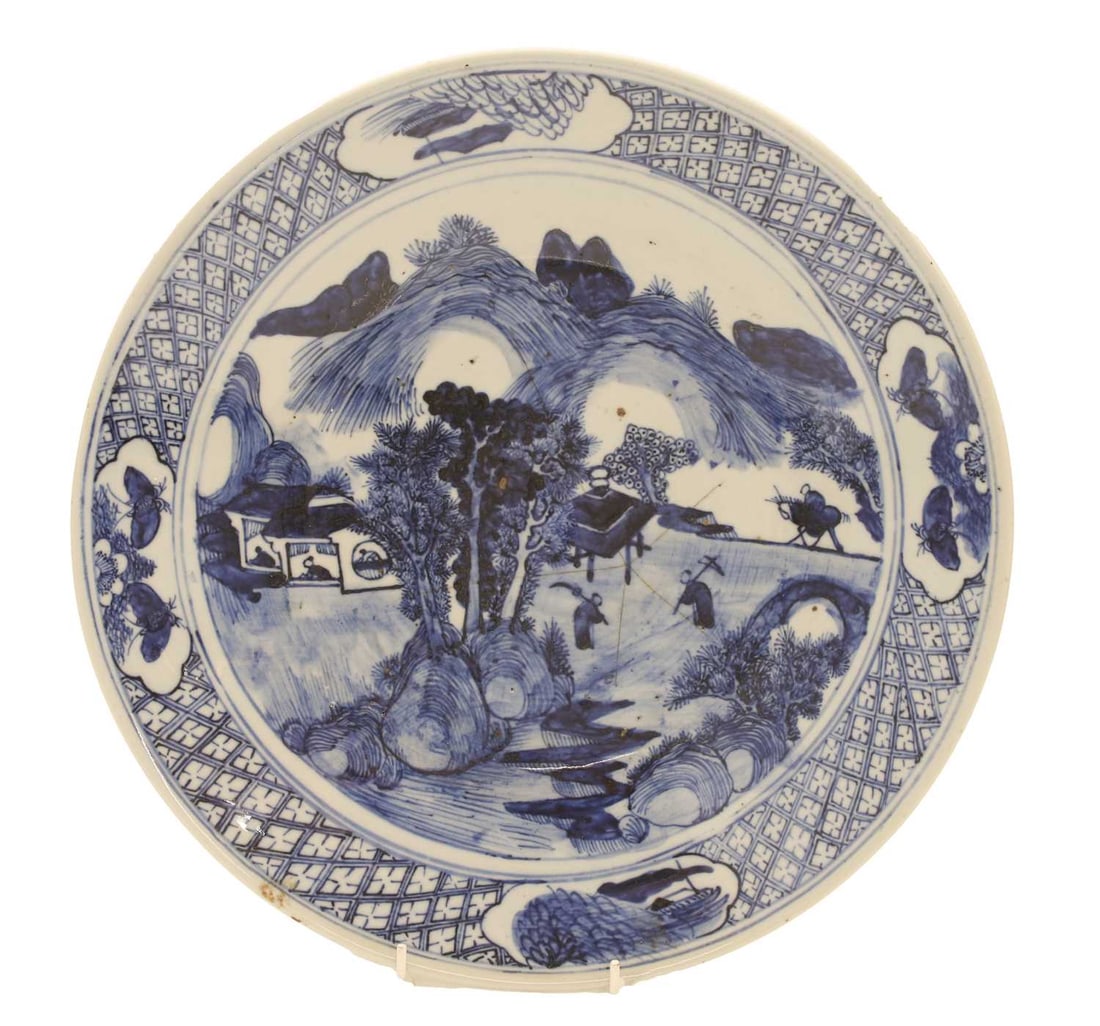 A large Chinese blue and white plate, late 19th century,: A large Chinese blue and white plate, late 19th century, the centre painted with figures in a rural landscape, mountains beyond, the rim with a diaper pattern border between reserves of insects and