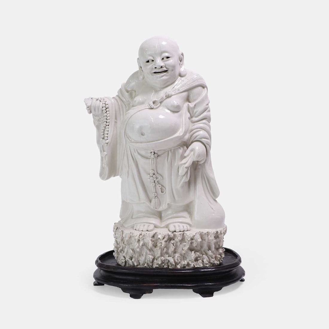 A Chinese blanc de Chine figure, 19th century,: A Chinese blanc de Chine figure, 19th century, standing on a rock, wearing a garment with brickwork design tied loosely to the chest, exposing his right shoulder and a rotund bare belly, holding a ros