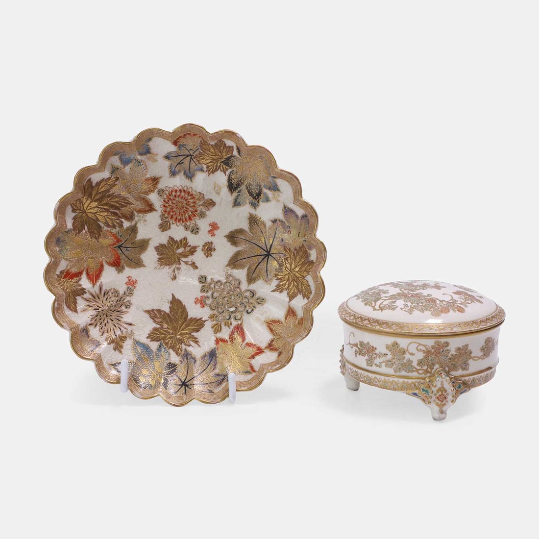 Two Japanese Satsuma ware, early 20th century,: Two Japanese Satsuma ware, early 20th century, comprising a box and cover, raised on three feet, decorated with stylised foliage, with a Kinkozan zo mark in red to base, and a lobed saucer, painted wi