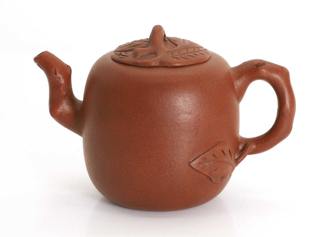 A Chinese Yixing zisha teapot, 20th century,: A Chinese Yixing zisha teapot, 20th century, modelled naturalistically, with moulded decoration of a leaf and an inscription to the body, the cover in the form of a cluster of leaves, the spout and ha