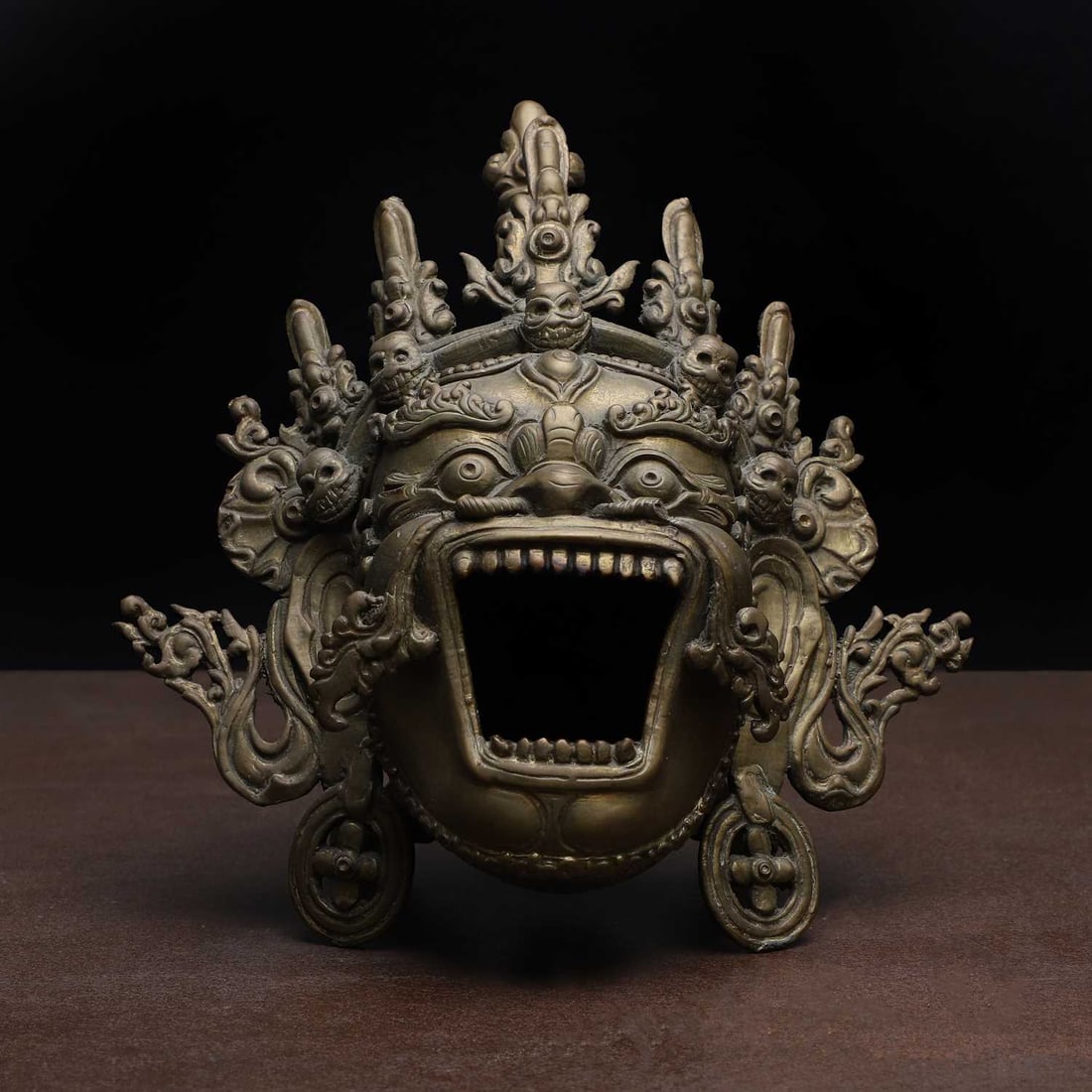 A Tibetan bronze incense burner, 19th-20th century,: A Tibetan bronze incense burner, 19th-20th century, the tripod incense burner in the form of a Mahakala mask, modelled with a wrathful expression with large bulging eyes beneath bushy brows, centred