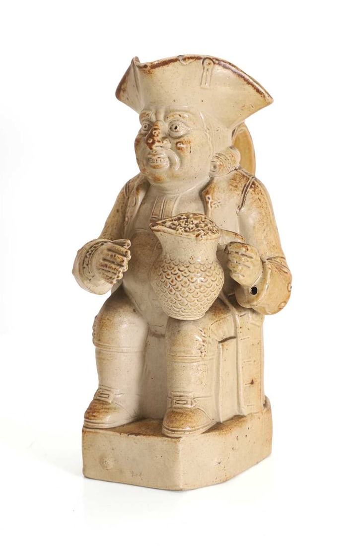 A Staffordshire salt glazed stoneware Toby jug, late 18th to early 19th century,: A Staffordshire salt glazed stoneware Toby jug, late 18th to early 19th century, modelled in a seated position, holding a jug of beer 11.5cm wide, 19.5cm deep, 23.5cm high Condition Report: There are