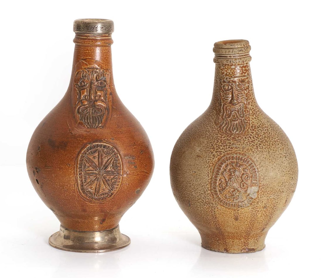 Two Bellarmine stoneware jugs, 17th century, German,: Two Bellarmine stoneware jugs, 17th century, German, of typical form, one with silver mounts, the foot by Preece & Willicombe, London 1939, the collar London 1889, 23.3 and 21.5cm high 2