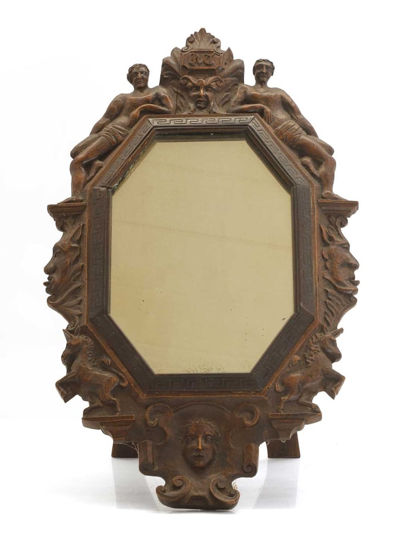 A carved oak easel back mirror, 19th century,: A carved oak easel back mirror, 19th century, surmounted with a Green Man mask, flanked by a pair of figures above rearing horses 25.5cm wide, 42.5cm high Condition Report: Part of the Greek key slip