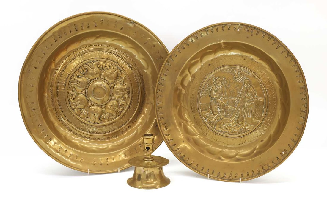 A collection of brass items, possibly 16th or 17th century,: A collection of brass items, possibly 16th or 17th century, comprising two alms dishes, German, each with an inscription to the central well, and a capstan type candlestick, with banded socket over a