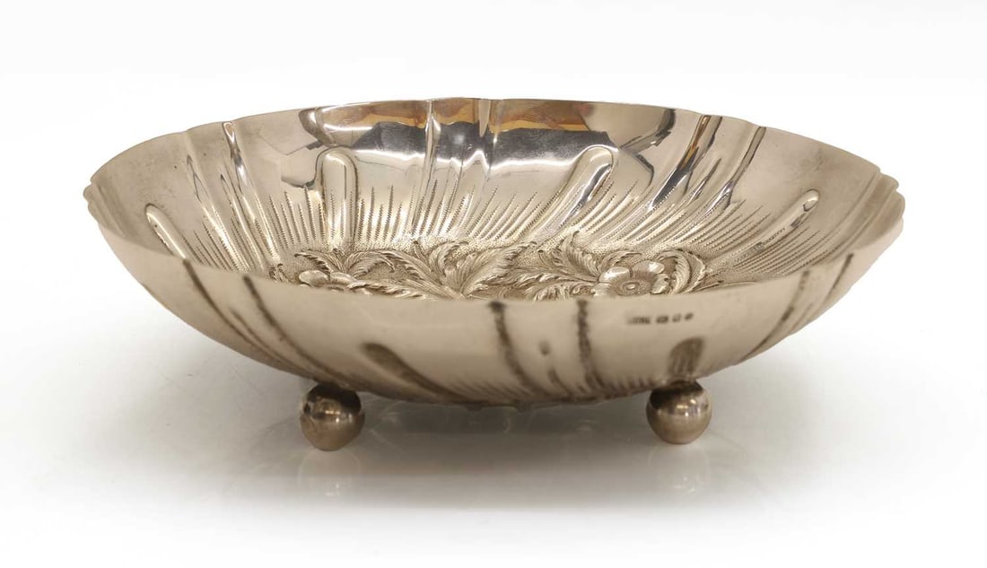 A silver bowl,: A silver bowl, by J H J, London, 1975, with foliate of gourds and strawberries cast to the centre and terminating on four ben feet 24cm diameter, 17.7ozt