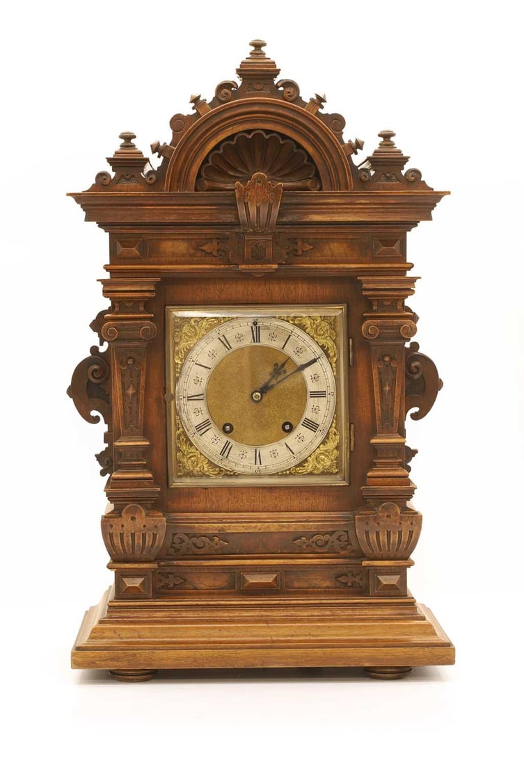 A German walnut cased mantel clock, late 19th century,: A German walnut cased mantel clock, late 19th century, of unusual large proportions, the profusley carved, scrolled and columned case surrounding a gilt and metal face with roman numerals, raised over