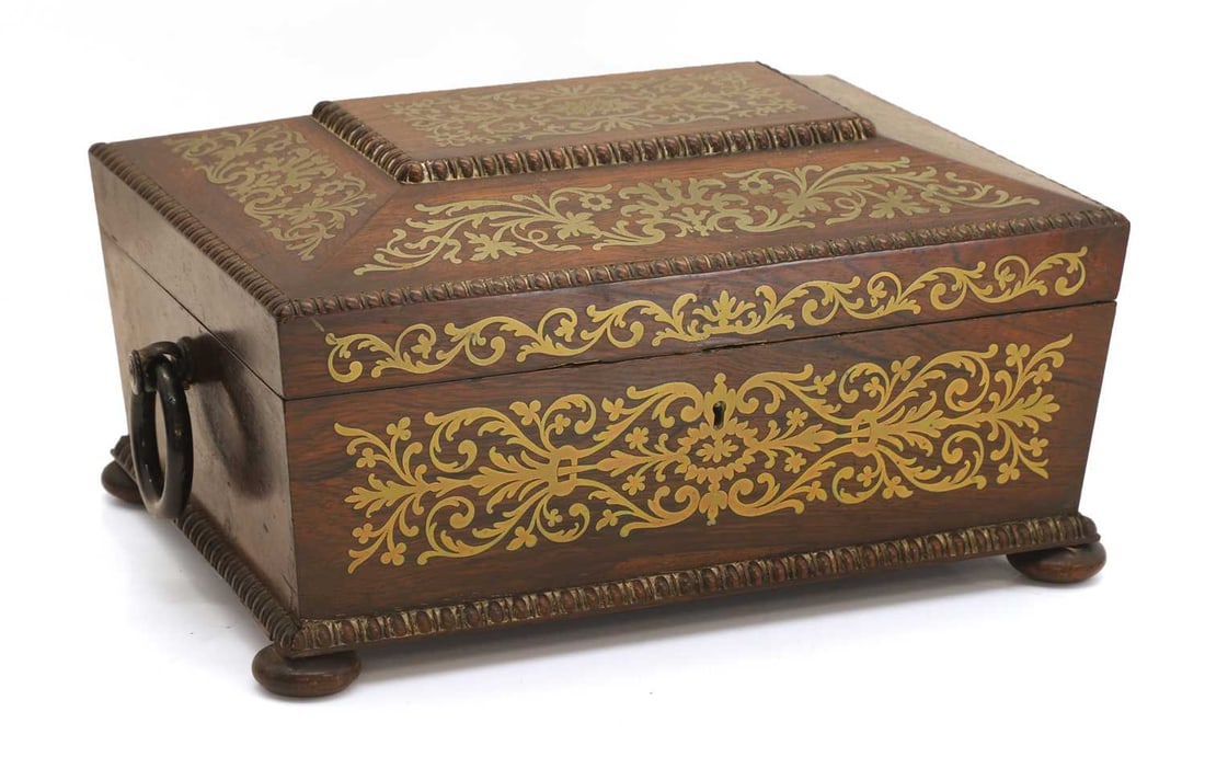 A Regency rosewood and cut-brass inlaid box, early 19th century,: A Regency rosewood and cut-brass inlaid box, early 19th century, of sarcophagus form, with egg-and-dart borders, complete with a lined and fitted interior 31.5cm wide, 23.5cm deep, 15.8cm high