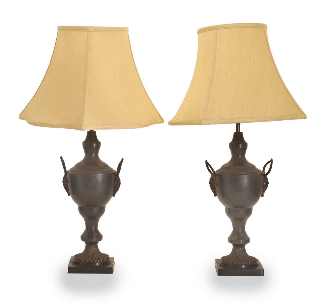 A pair of bronzed metal urn table lamps, 20th century,: A pair of bronzed metal urn table lamps, 20th century, each with looped handles moulded as bunches of grapes and standing on fluted circular to square bases, fitted with cream silk shades 20cm wide, 1