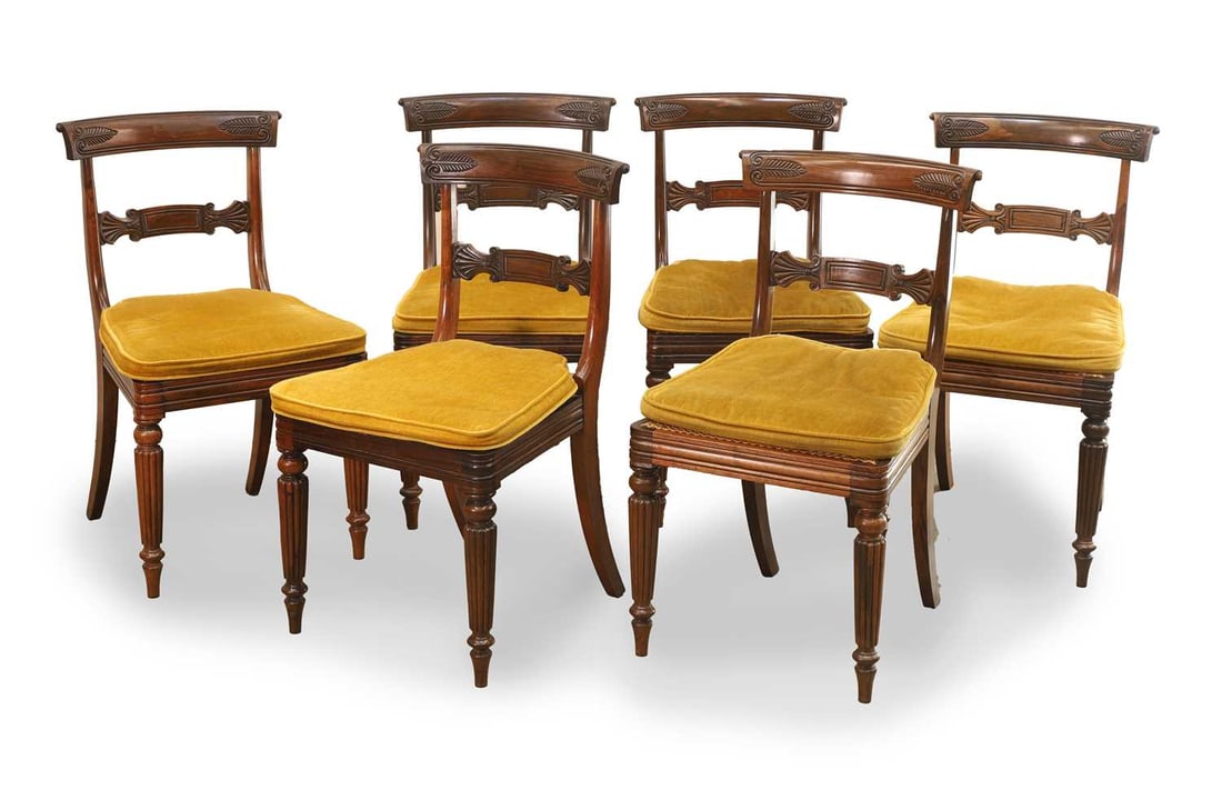 A set of six rosewood dining chairs, circa 1825,: A set of six rosewood dining chairs, circa 1825, in the manner of Gillows, with floliate carved bar back splats, and caned seats, terminating on fluted legs, with mustard upholstered seat cushions 45c