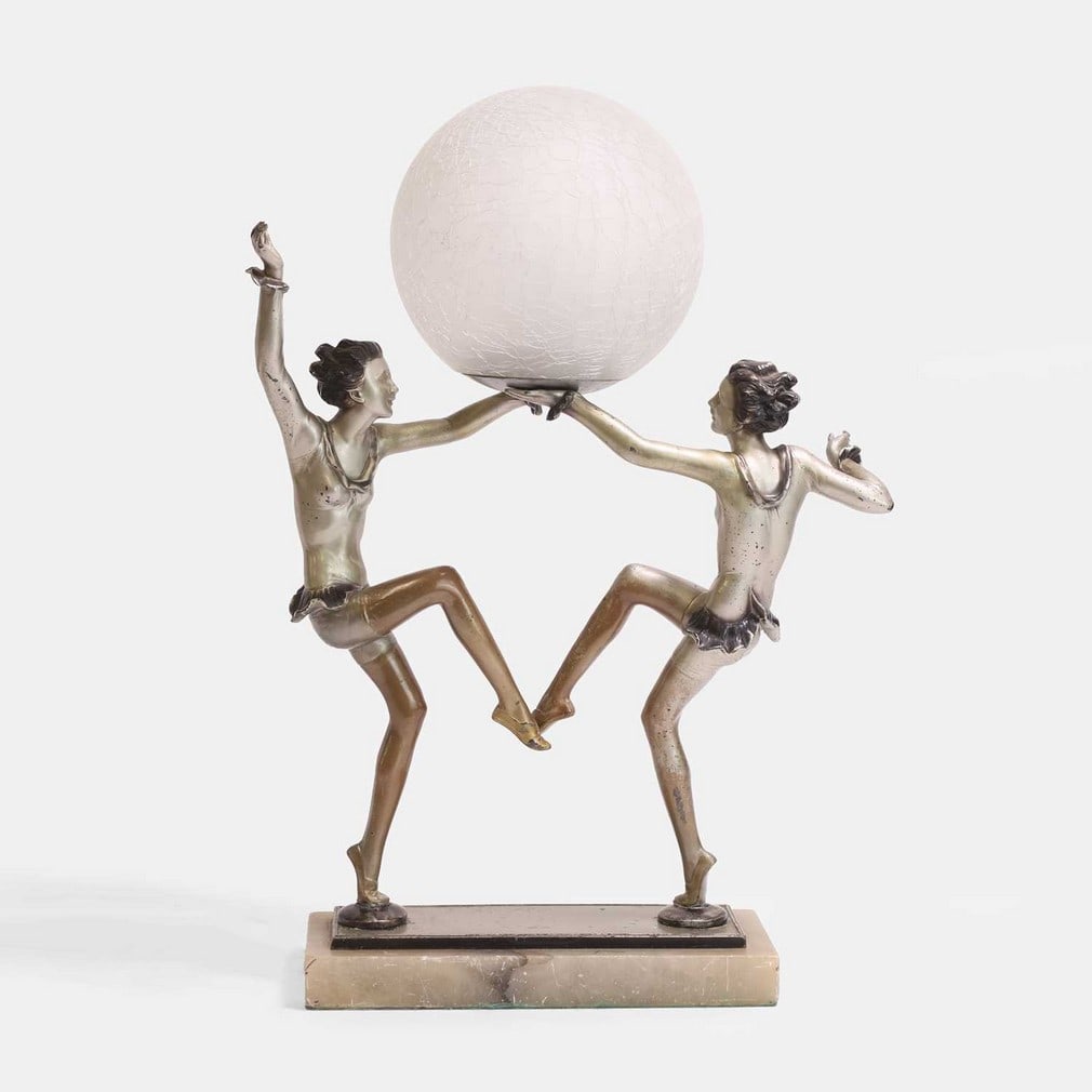 Art Deco, a double figurative table lamp,: Art Deco, a double figurative table lamp, circa 1930, spelter, with a glass globular shade, raised on a marble base (31cm wide, 15cm deep, 45cm high) Condition Report: The figures are loose in the