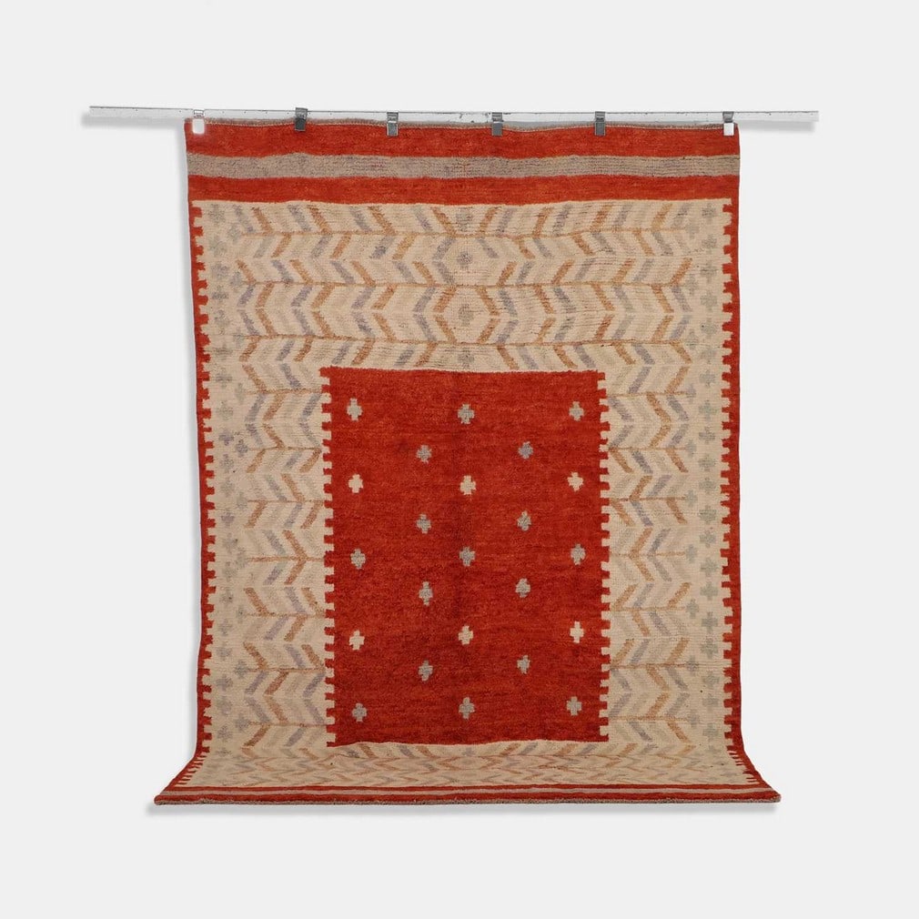 Scandinavian-inspired, a wool rug,: Scandinavian-inspired, a wool rug, of recent manufacture, the central panel with cross motifs to a rust-red ground, surrounded by a geometric border in tones of pale grey and brown to a cream ground (