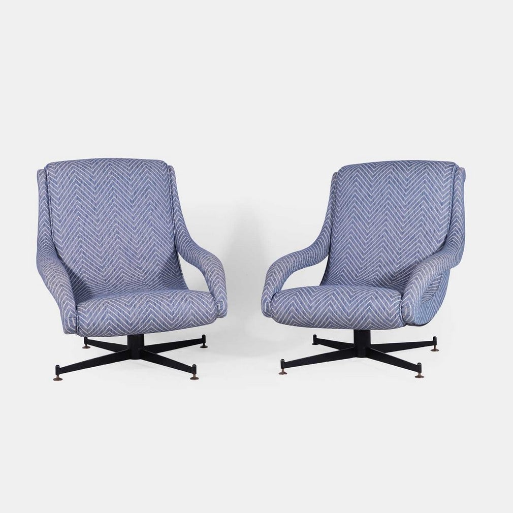 Attributed to Minotti, a pair of armchairs,: Attributed to Minotti, a pair of armchairs, circa 1960s, Italian, later upholstered in a light-blue herringbone pattern fabric, each with curved armrests, raised on a black painted-metal swivel 'X'-fo