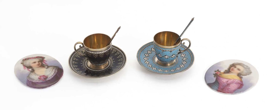 A pair of silver and enamelled teacups and saucers,: A pair of silver and enamelled teacups and saucers, both with patterned enamelled decoration one in light blue and the other in a deep burgundy, stamped '925', with matching spoons and a pair of