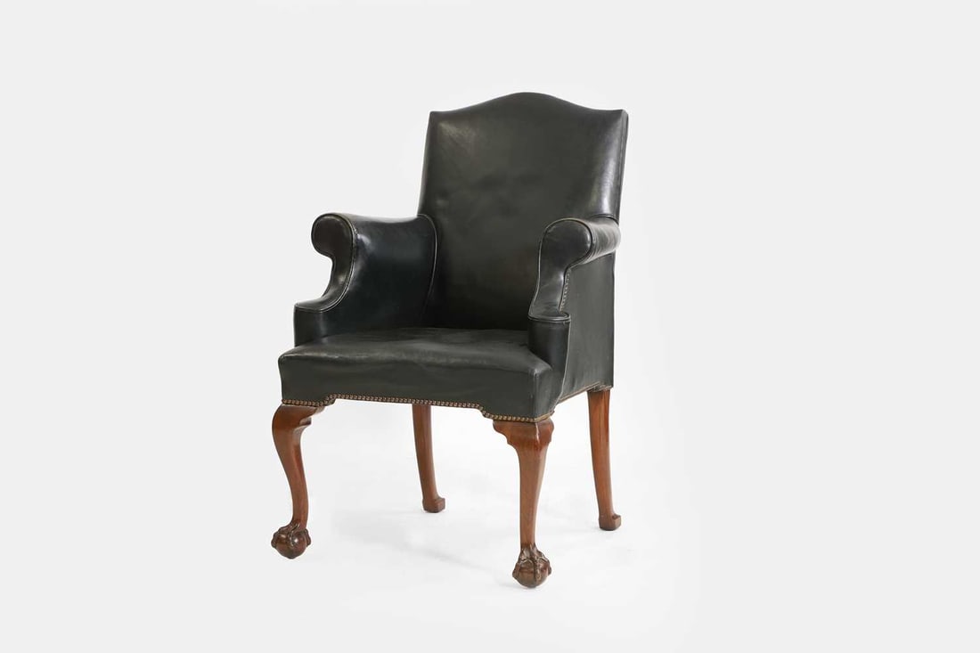 A mahogany and leather armchair in the George II taste, early 20th century,: A mahogany and leather armchair in the George II taste, early 20th century, with a camel back and outswept arms, raised on cabriole front supports, terminating in claw and ball feet 74cm wide, 74cm