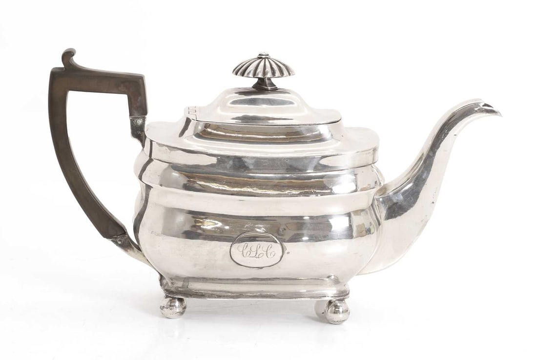 A silver Georgian teapot,: A silver Georgian teapot, possibly by Henry Nutting, London, 1810, terminating on bun feet, with ebonised handle and finial 27.5cm wide, total 17.9ozt
