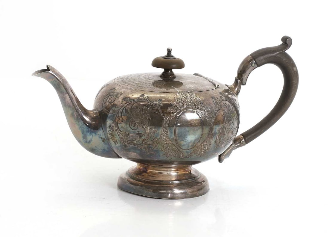 A silver teapot,: A silver teapot, by Cooper Brothers & Sons Ltd Sheffield, 1916, with ebonised handle and finial topped lid, profusley detailed, with engraved presentation message to the lid 22cm wide, 12cm high,