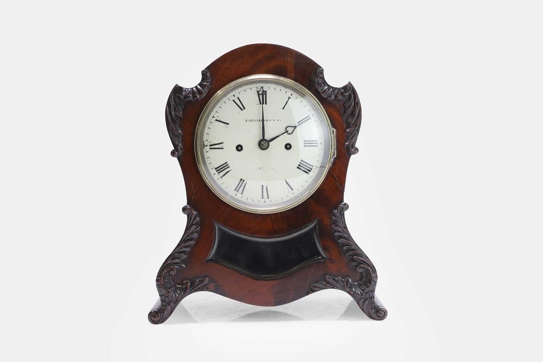A Regency mahogany bracket clock, early 19th century, by Brockbank & Atkins,: A Regency mahogany bracket clock, early 19th century, by Brockbank & Atkins, the circular dial with Roman numerals, enclosed within a shaped balloon case carved with scrolling foliate and acanthus